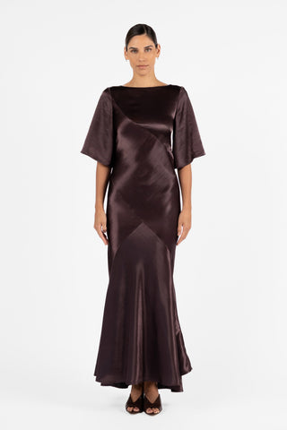 One Fell Swoop Moni Gown in Aubergine featuring a bateau neckline, sculptural bias panelling and elbow-length sleeves.