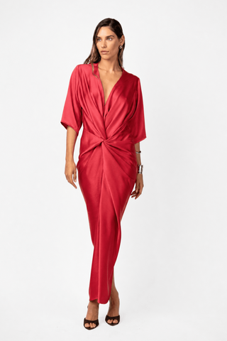 Model wearing the Alex Kimono Maxi in Venetian Red. Lustrous satin drapes through a plunging neckline and twisted waist, creating fluid movement through the full-length silhouette.
