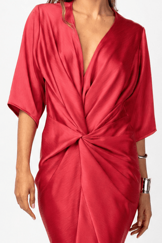 Model wearing the Alex Kimono Maxi in Venetian Red. Lustrous satin drapes through a plunging neckline and twisted waist, creating fluid movement through the full-length silhouette. CLOSE UP TWIST DETAIL