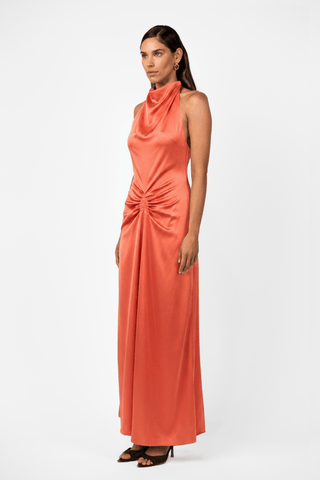  Front view of the One Fell Swoop Caira Gown in Clay showcasing a sculptural halter neckline, liquid satin and elegant full length silhouette. 